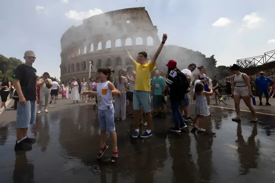 گردشگران در مقابل کولوسئوم (Colosseum) زیر مه پاشهای آب برای خنک شدن