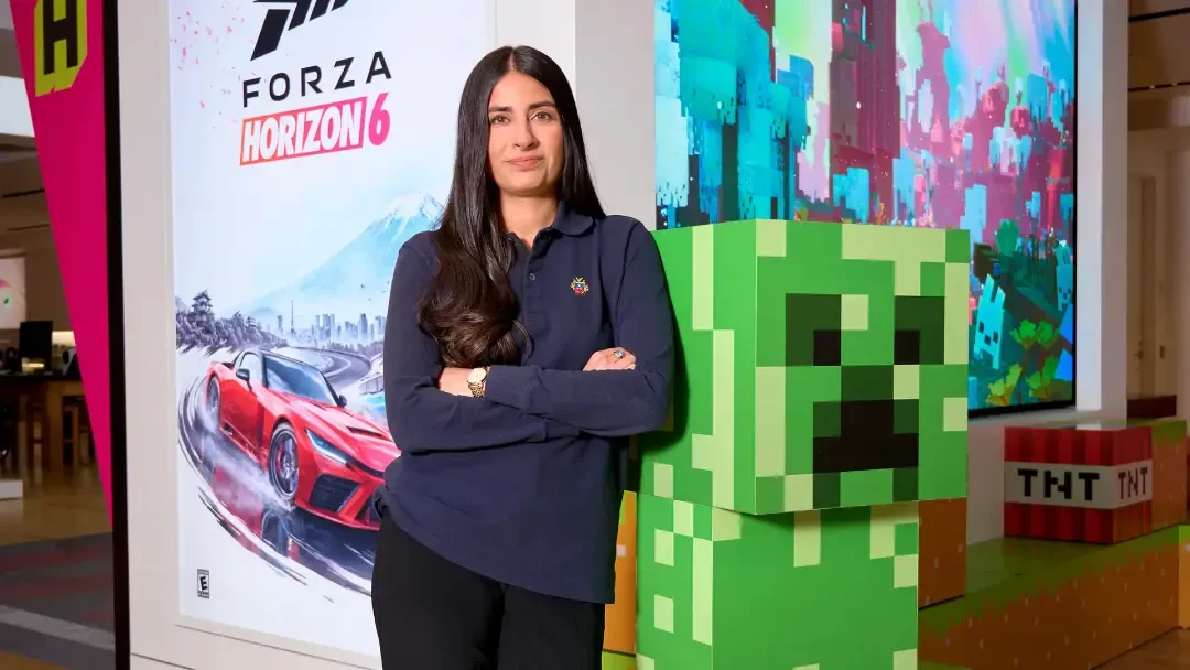 آشا شارما (Asha Sharma) در کنار پوسترهای بازیهای ایکس باکس (Xbox) در فروشگاه مایکروسافت
