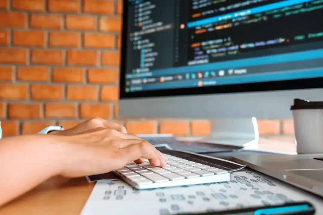 کدهای برنامهنویسی وردپرس روی مانیتور در کنار دست برنامهنویس روی کیبورد