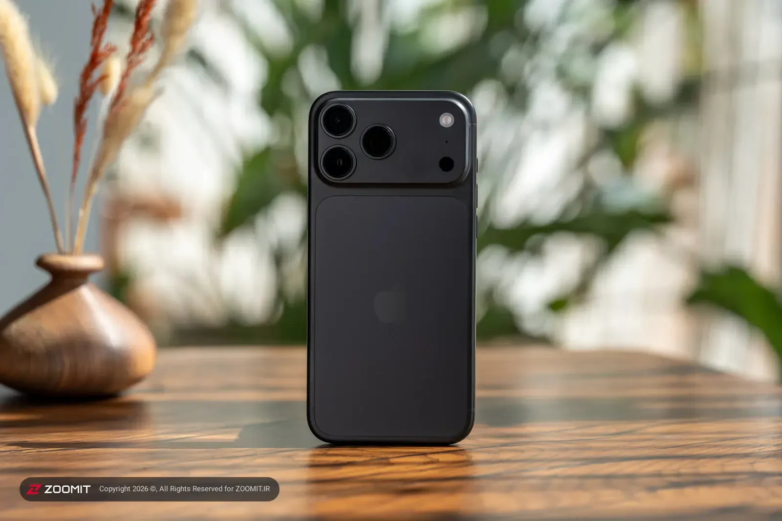 گوشی آیفون ۱۸ پرو مکس (iPhone 18 Pro Max) با بدنه مشکی روی میز چوبی