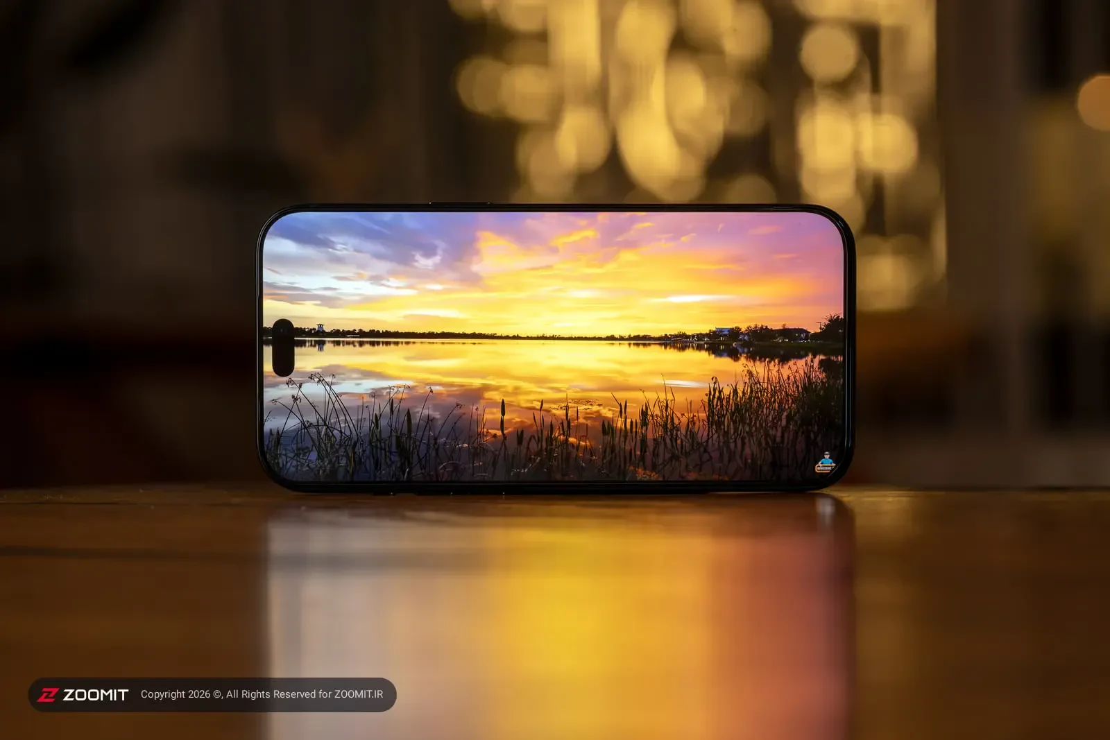 نمایشگر گوشی آیفون ۱۸ پرو مکس (iPhone 18 Pro Max) با تصویر غروب دریاچه